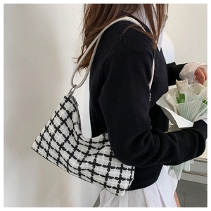 Classic black and white checkered tweed shoulder bag shown on model with elegant bouquet