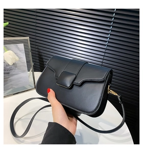 Detail of minimalist black matte leather square bag with matching square buckle and strap