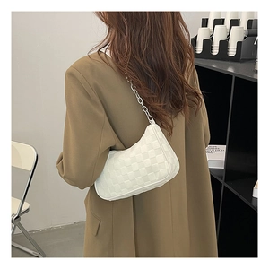 Rear view of a model wearing a white checkered hobo bag with silver chain strap