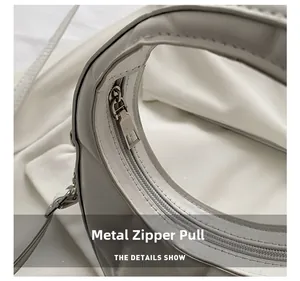 Close-up of premium metal zipper puller and precise stitching on white leather bag