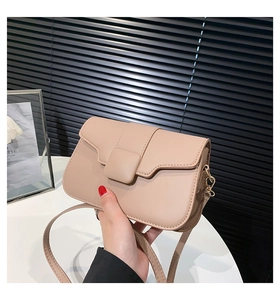 Detailed close-up of beige square crossbody bag with fine leather texture and flap cover