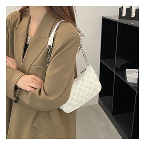 Detail view of checkerboard pattern shoulder bag with silver chain strap on model