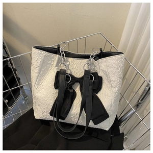 Vue détaillée d'un sac cabas plissé blanc avec grand nœud noir et chaîne argentée