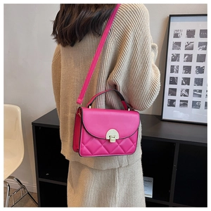 Detail of fuchsia quilted crossbody bag featuring a golden buckle and leather strap