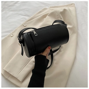 Detail view of black cylindrical PU leather crossbody bag with adjustable strap and silver zipper