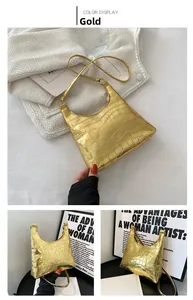 Close-up of gold crocodile pattern handbag with metallic finish and thin shoulder strap