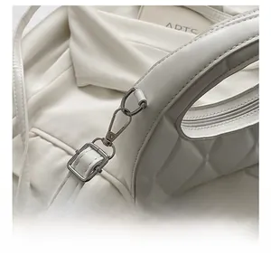 Detailed view of silver metal hook, adjustable strap and zipper on white quilted bag