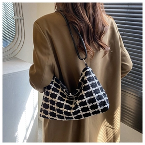 Detail of black and white checkered plush hobo bag worn with an autumn blazer