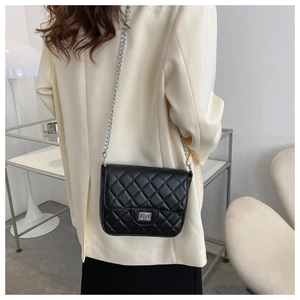 Close-up of black quilted leather crossbody bag with silver chain and metal twist lock