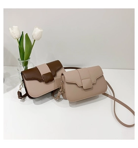 Detail of minimalist two-tone PU leather crossbody bag featuring gold hardware buckles