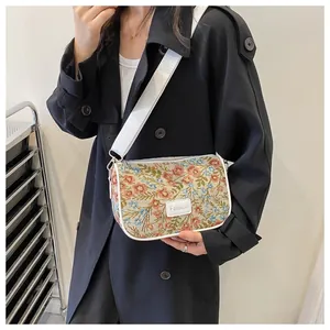Detail of floral crossbody bag with wide white strap and Fashion label on trench coat