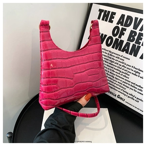 Close-up of vibrant pink crocodile embossed half-moon tote bag with glossy texture