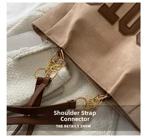 Detail of the golden metal chain link and strap connection on the brown suede tote bag