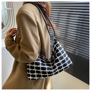 Detail of checkered tote bag with black and white tweed texture on a model shoulder