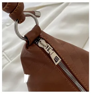 Detail of smooth metal zipper and silver ring handle on brown embossed leather bag