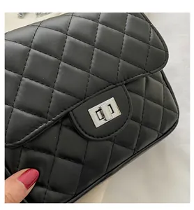 Close-up of black quilted leather texture and silver metallic twist lock on the handbag