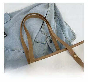 Détails d'un sac cabas en toile montrant les anses en cuir et les rivets dorés