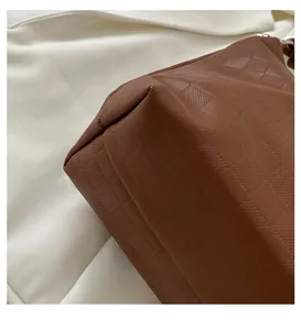 Detail view of the brown leather bag bottom featuring checkered embossed texture and stitching