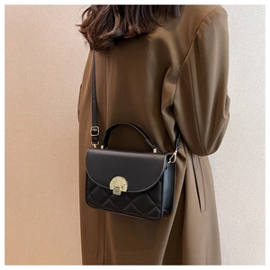 Close-up of black quilted leather crossbody bag with vintage gold metal lock and top handle