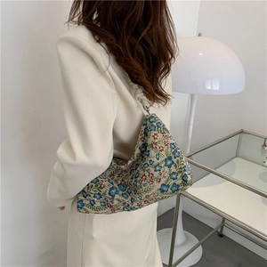 Floral embroidered underarm shoulder bag with knotted handle shown in a minimalist interior