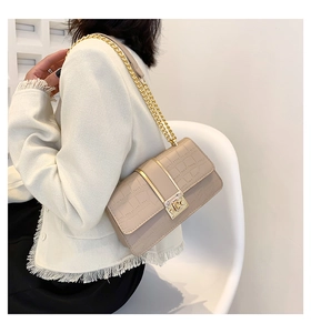 Close-up of beige crocodile pattern handbag with golden chain strap and swivel lock