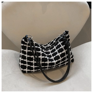 Detail of black and white plaid tweed shoulder bag with silver hardware on a chair