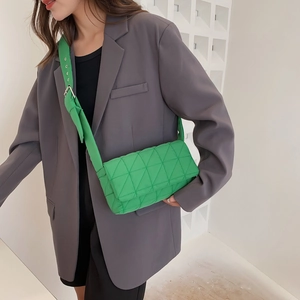 Bright green quilted crossbody bag with wide strap displayed on a female model
