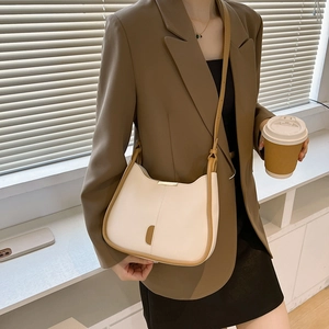 Sac hobo beige chic avec bordure en cuir marron et une forme en demi-lune minimaliste