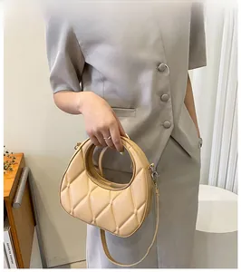 Detail of beige quilted crescent bag with a unique circular handle and thin strap