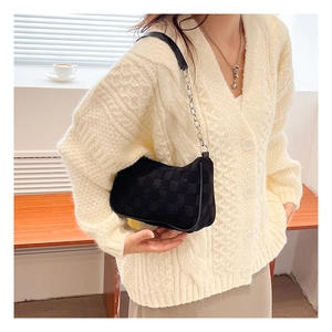 Detail of black woven shoulder bag featuring textured grid pattern and silver chain strap