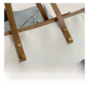 Détail d'un sac cabas en toile avec poignée en cuir renforcée et rivets dorés