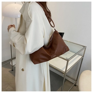 Macro detail of brown leather hobo bag with Fashion logo tag shown in style
