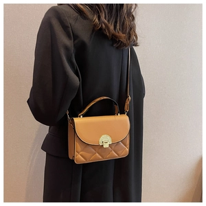 Detail of a brown quilted crossbody bag featuring a vintage gold semicircular buckle
