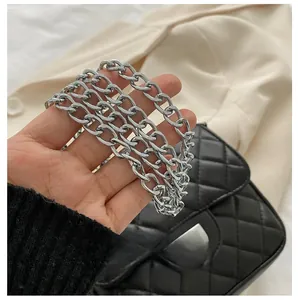 Close-up of a chunky silver metal chain strap on a black quilted crossbody bag