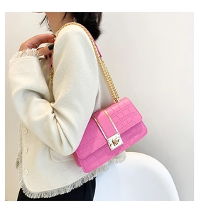 Nahaufnahme der pinken Kunstledertasche mit Kroko-Prägung und goldener Kette am Model
