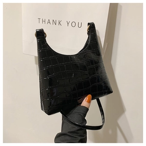 Detail of black crocodile embossed handbag showing glossy texture and gold metal ring