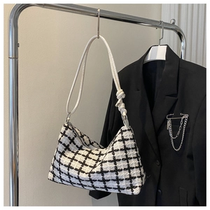 Detail of checkered tweed tote bag with a white leather knotted shoulder strap