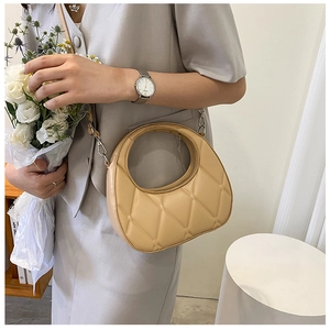 Detail of light brown crescent crossbody bag with quilted rhombic pattern on shoulder
