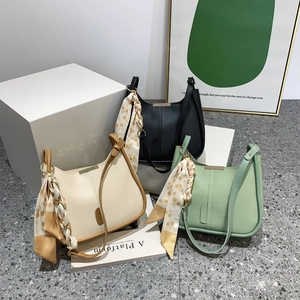 Trois sacs à bandoulière minimalistes en beige, noir et vert avec des foulards en soie décoratifs