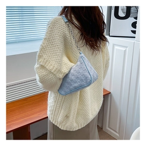 Detail of light blue woven plaid shoulder bag with silver chain and leather strap