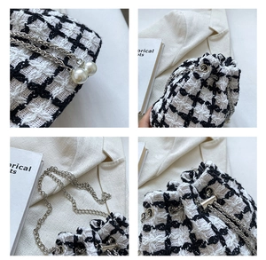 Detail of tweed bucket bag showing silver chain strap and large faux pearl accents