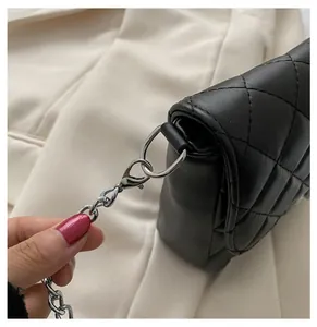 Close-up of bright silver metal hooks and chain on a black quilted leather bag