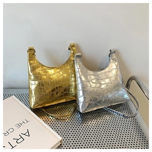 Detailed view of silver and gold crescent bags with crocodile pattern on metal stool