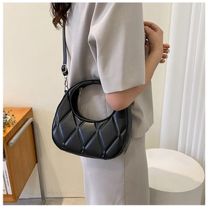 Detail of black quilted dumpling bag showing the crescent shape and silver zipper texture