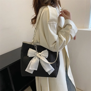 Sac cabas noir minimaliste avec nœud en organza blanc porté par un mannequin