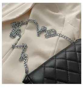Detailed view of black quilted crossbody bag with silver metal chain strap texture