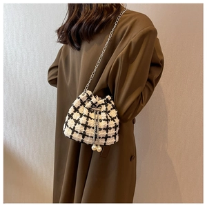 Detail of tweed bucket bag featuring black white plaid and large pearl drawstring charms