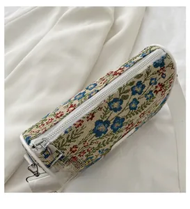 Close-up of vintage floral tapestry barrel bag with white canvas strap on soft fabric