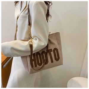 Detail of large tote bag with textured HOOTO lettering and metal chain strap