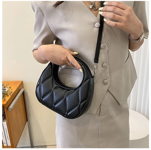 Detail of black crescent hobo bag featuring quilted pattern and circular cutout handle